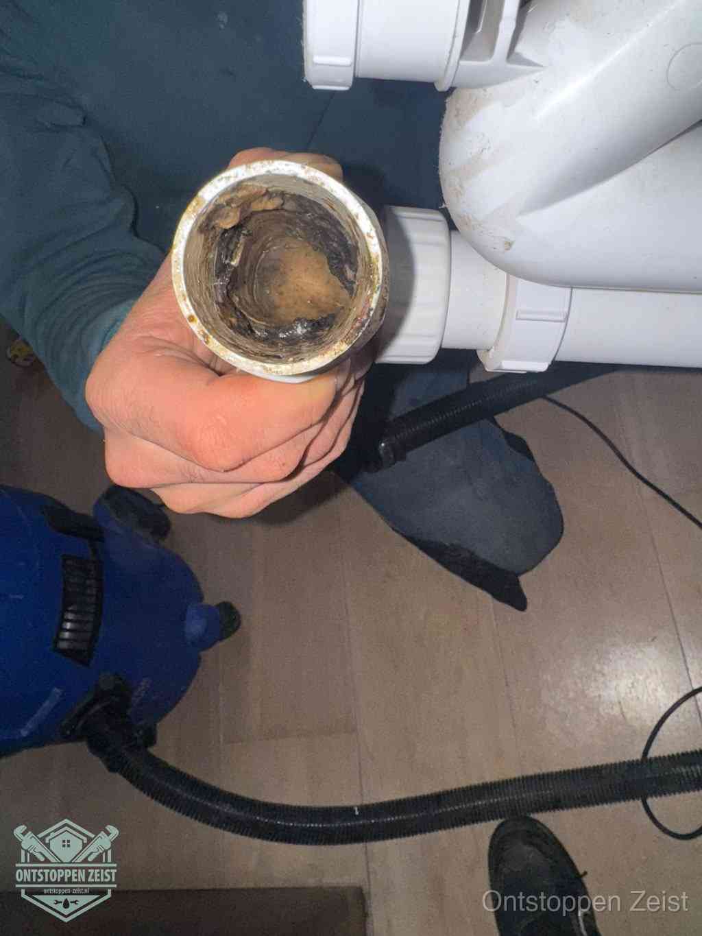 Een losgekoppelde afvoerbuis die van binnen volledig is dichtgeslibd met vet en aanslag, de meest voorkomende oorzaak van een verstopte gootsteen in Zeist Een losgekoppelde afvoerbuis die van binnen volledig is dichtgeslibd met vet en aanslag, de meest voorkomende oorzaak van een verstopte gootsteen in Zeist