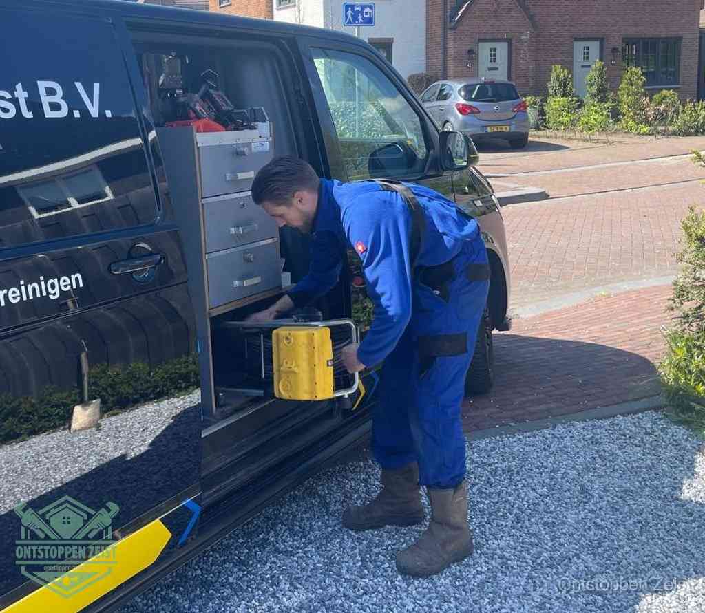 Een monteur pakt buiten op de oprit gereedschap uit de bedrijfsbus, het moment om een professional in te schakelen voor een verstopte afvoer in Zeist