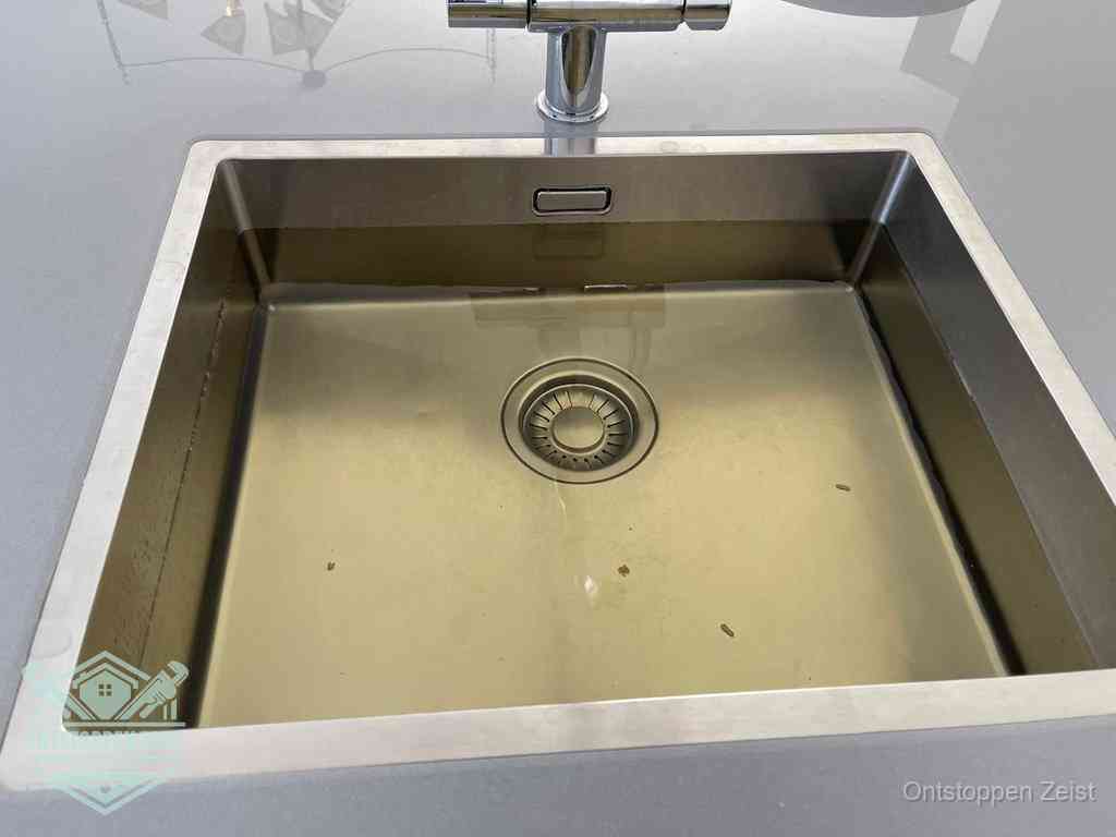 Stilstaand water in een rvs spoelbak dat niet wegloopt, een duidelijk signaal van een gootsteenverstopping in Zeist