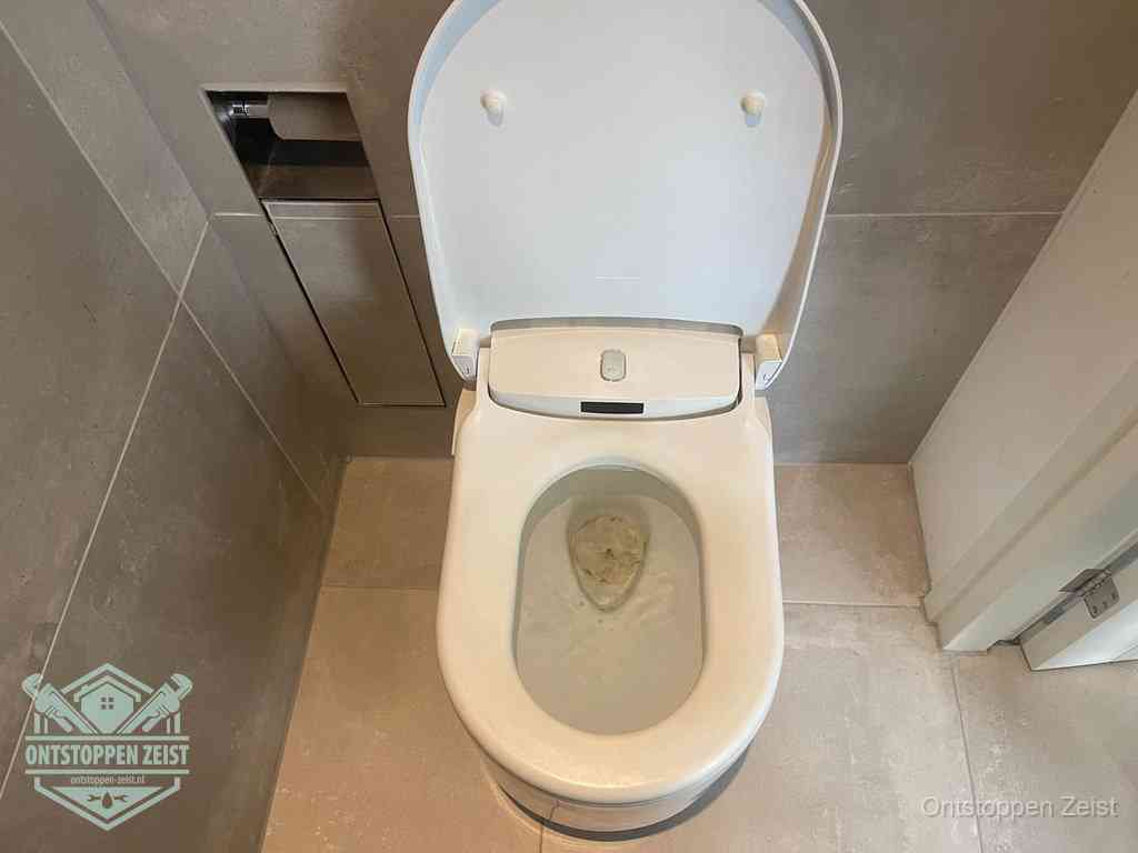 Een wit hangtoilet waarin een prop wc-papier op het water blijft drijven, een duidelijk signaal van een verstopte wc in Zeist