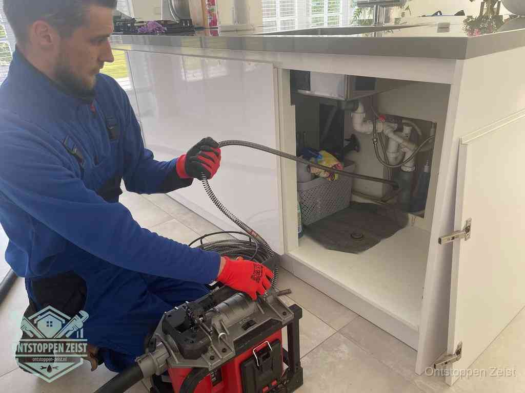 Een monteur reinigt de keukenafvoer grondig met een veermachine om terugkerende gootsteenverstoppingen te voorkomen in Zeist Een monteur reinigt de keukenafvoer grondig met een veermachine om terugkerende gootsteenverstoppingen te voorkomen in Zeist