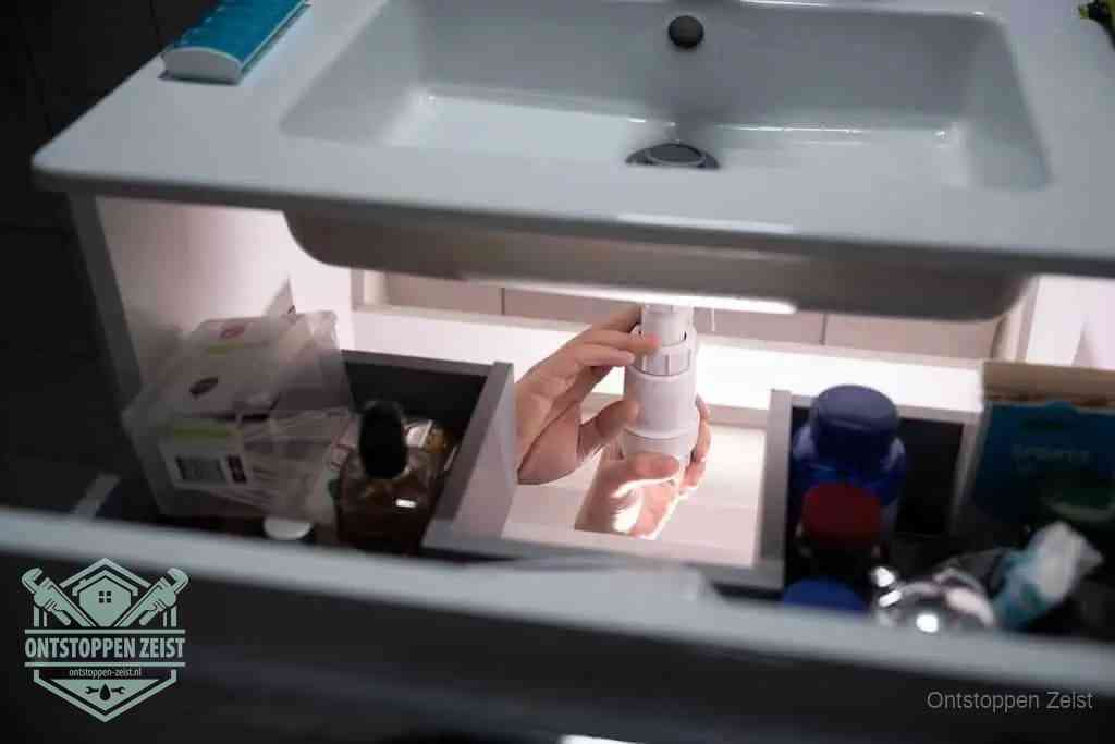 Een pompfles met zeep boven een wastafel in de toiletruimte, de warm water en afwasmiddel-methode om de wc te ontstoppen in Zeist Een pompfles met zeep boven een wastafel in de toiletruimte, de warm water en afwasmiddel-methode om de wc te ontstoppen in Zeist