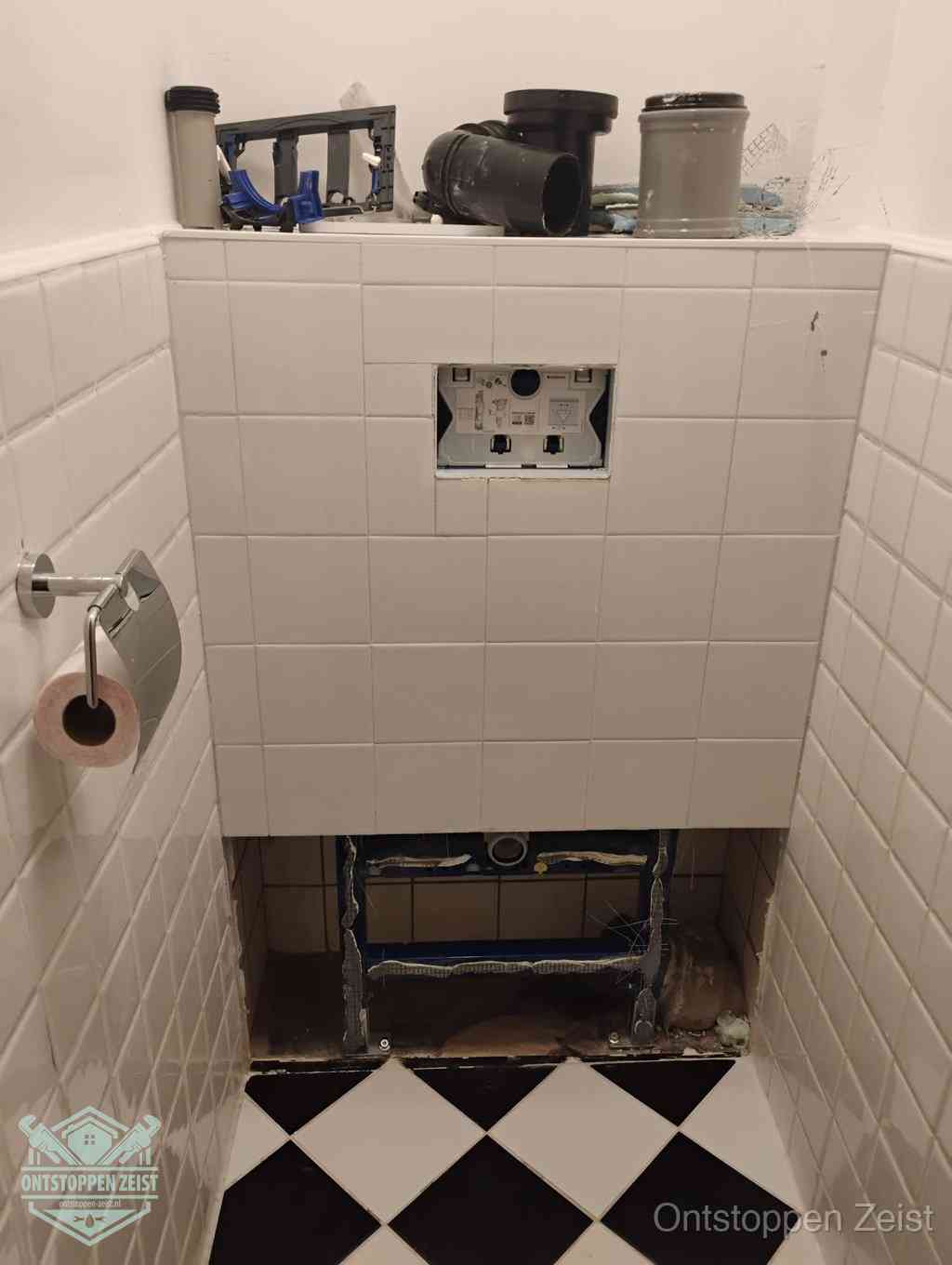 Een toiletruimte waar het hangtoilet en de inbouwreservoir-onderdelen zijn vrijgelegd voor onderhoud, periodiek nazicht voorkomt een wc-verstopping in Zeist Een toiletruimte waar het hangtoilet en de inbouwreservoir-onderdelen zijn vrijgelegd voor onderhoud, periodiek nazicht voorkomt een wc-verstopping in Zeist