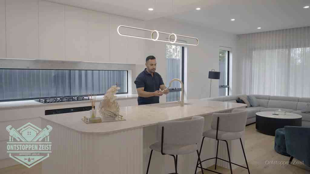 Een bewoner bij de keukenspoelbak die zelf aan de slag gaat met een verstopte gootsteen in Zeist Een bewoner bij de keukenspoelbak die zelf aan de slag gaat met een verstopte gootsteen in Zeist